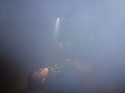 Das Bild zeigt ein Szenarientraining für Ersthelfer bzw. First Responder bei schlechten Lichtverhältnissen. In einem dunklen, staubigen Raum versorgt der Ersthelfer den Verletzten unter zu Hilfe Nahme einer Stirnlampe. 